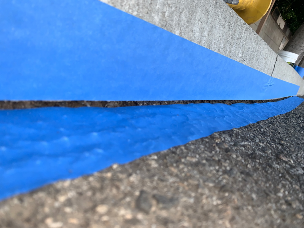 Concrete curb sealing with blue painter's tape during a project by Hollywood Handyman in Glendale, CA.