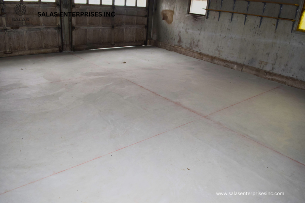 A newly poured concrete floor with layout markings in a garage or commercial space by Salas Enterprises, Inc in Elgin, IL