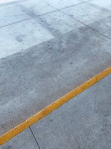 A concrete floor with a yellow painted line, showcasing commercial flooring work by Simply Construction in Las Vegas, NV.