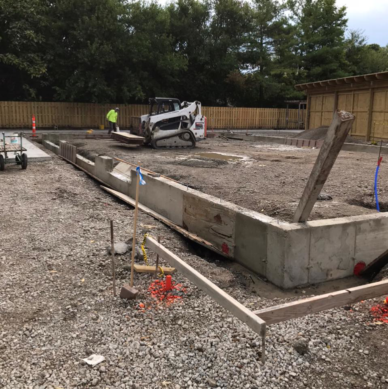 A construction site showing concrete foundation forms and a bobcat, handled by Complete Concrete of Indy, Inc. in Fishers, IN.