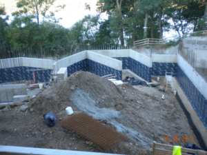 Concrete foundation walls with waterproofing membrane and rebar at a construction site by Crown Waterproofing Inc., Mount Vernon, NY.