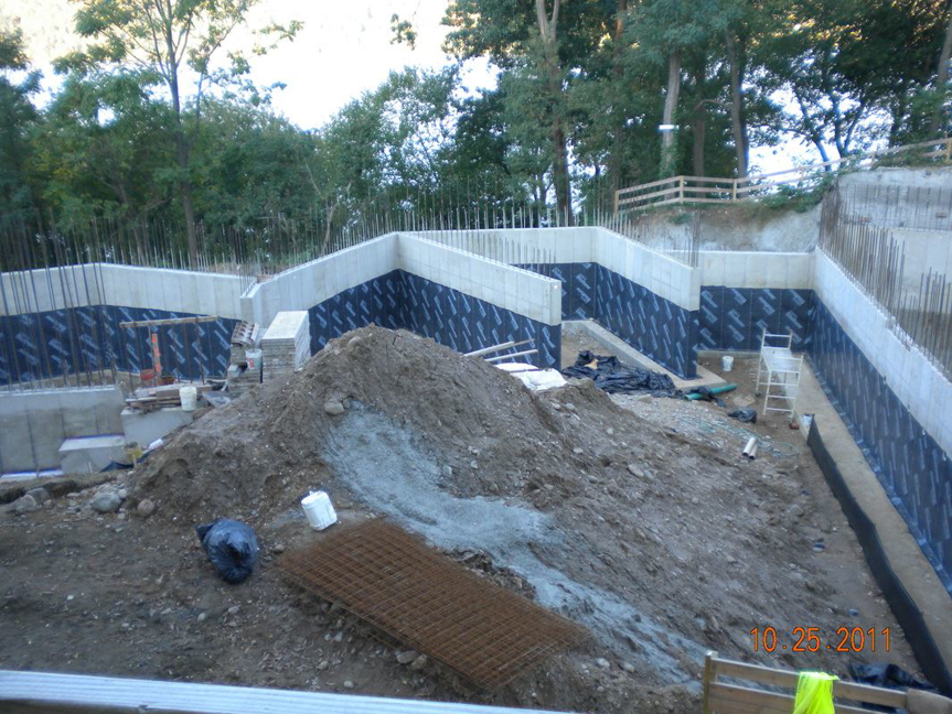 Concrete foundation walls with waterproofing membrane and rebar at a construction site by Crown Waterproofing Inc., Mount Vernon, NY.