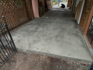 A newly installed concrete patio or walkway under a covered area by Unified Roofing and Exteriors in Gulf Shores, AL.