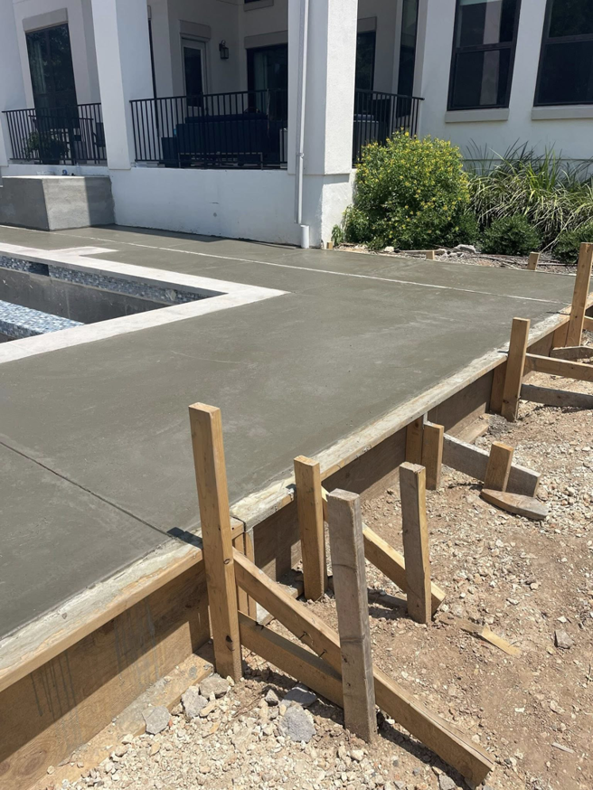 Freshly poured concrete pool decking with wooden forms during construction by Austin Pool Plastering in Austin, TX.