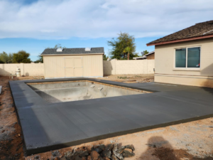 Concrete pool deck installation around an empty pool with a shed by Martin Jr's concrete in Surprise, AZ