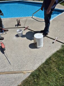 Workers from Woodford Bros., Inc. preparing concrete for a pool deck repair in Apulia Station, NY