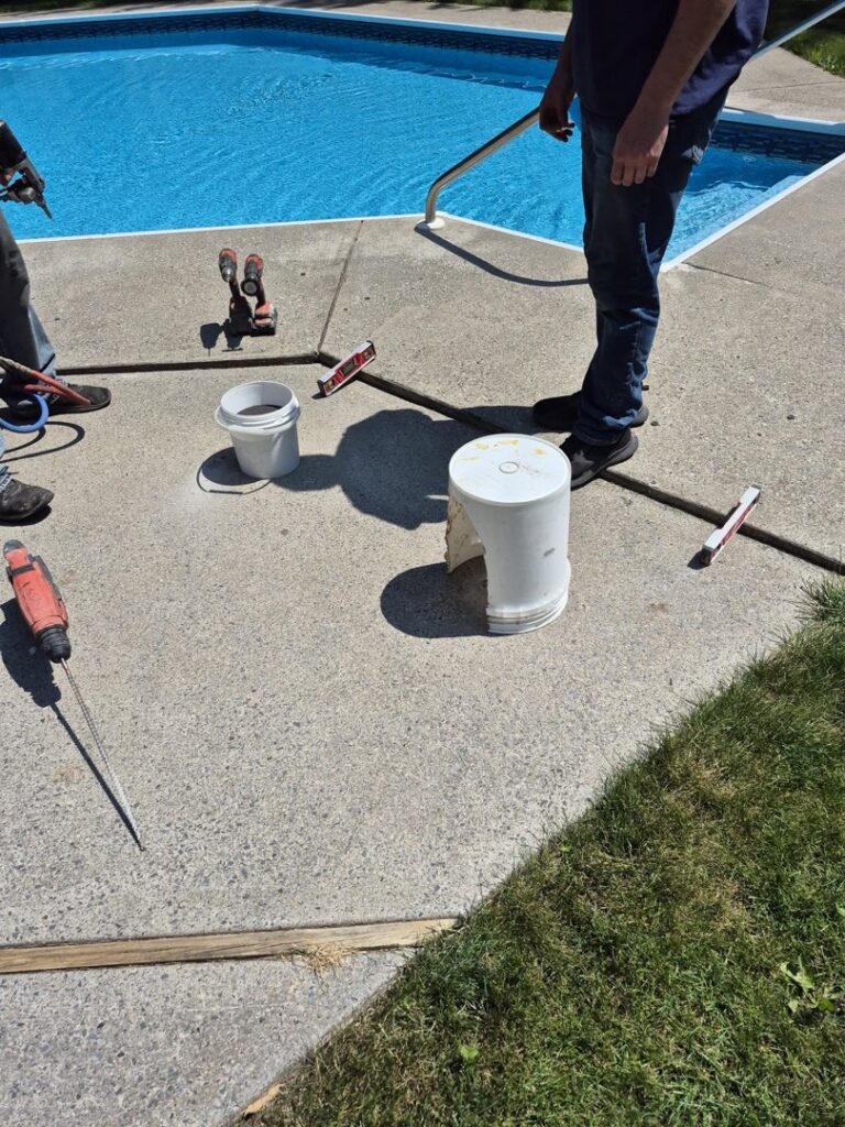 Workers from Woodford Bros., Inc. preparing concrete for a pool deck repair in Apulia Station, NY