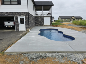 Newly poured concrete patio surrounding a swimming pool at a residential property by J&M Concrete Construction, LLC in Fayetteville, PA.
