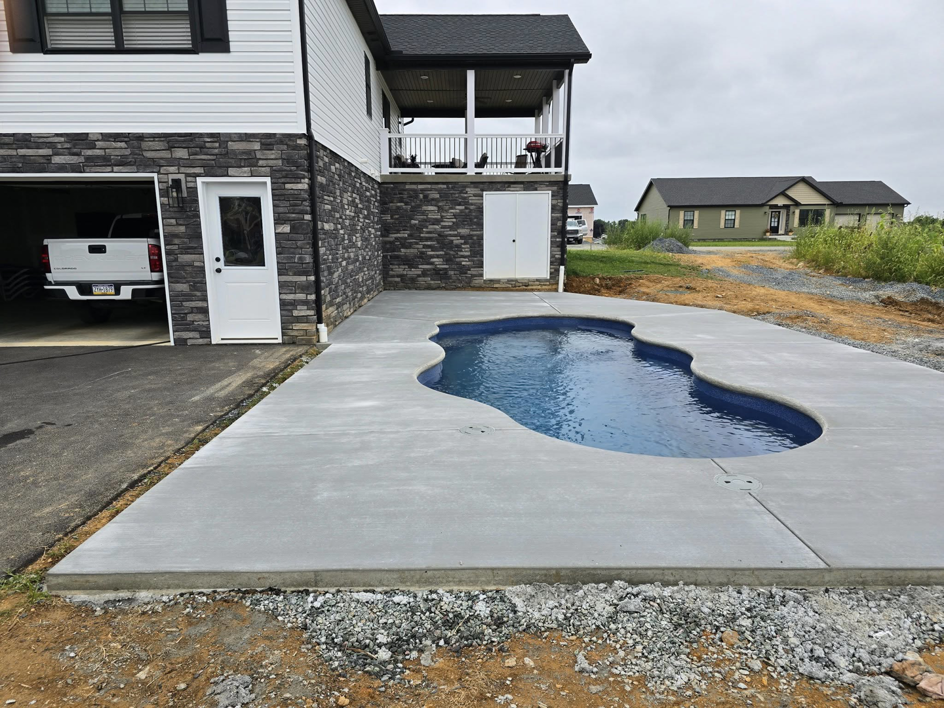 Newly poured concrete patio surrounding a swimming pool at a residential property by J&M Concrete Construction, LLC in Fayetteville, PA.