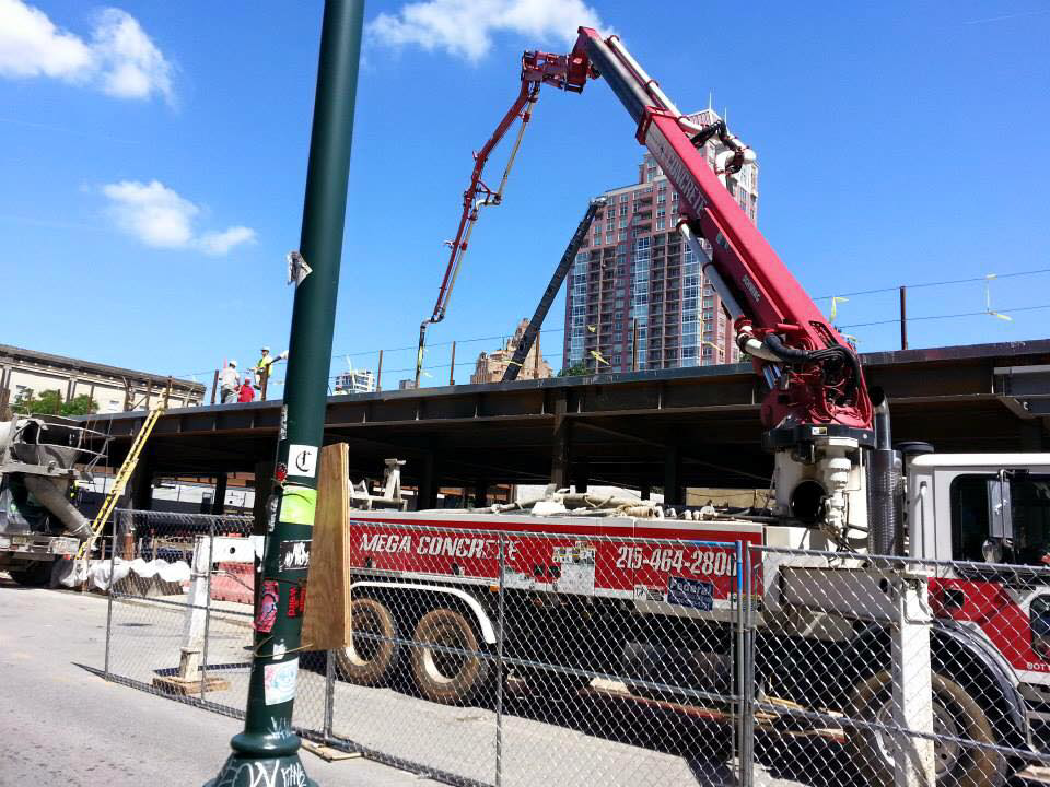 A Mega Concrete pump truck delivering concrete on a construction job site for Mega Construction in Philadelphia, PA.