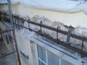 Concrete restoration work with exposed rebar on a building exterior by Snapp Industries, Inc. in Miami, FL