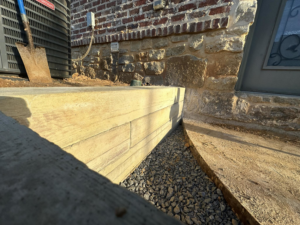 A newly constructed concrete retaining wall with gravel and a shovel by Louisiana Land Solutions in West Monroe, LA.