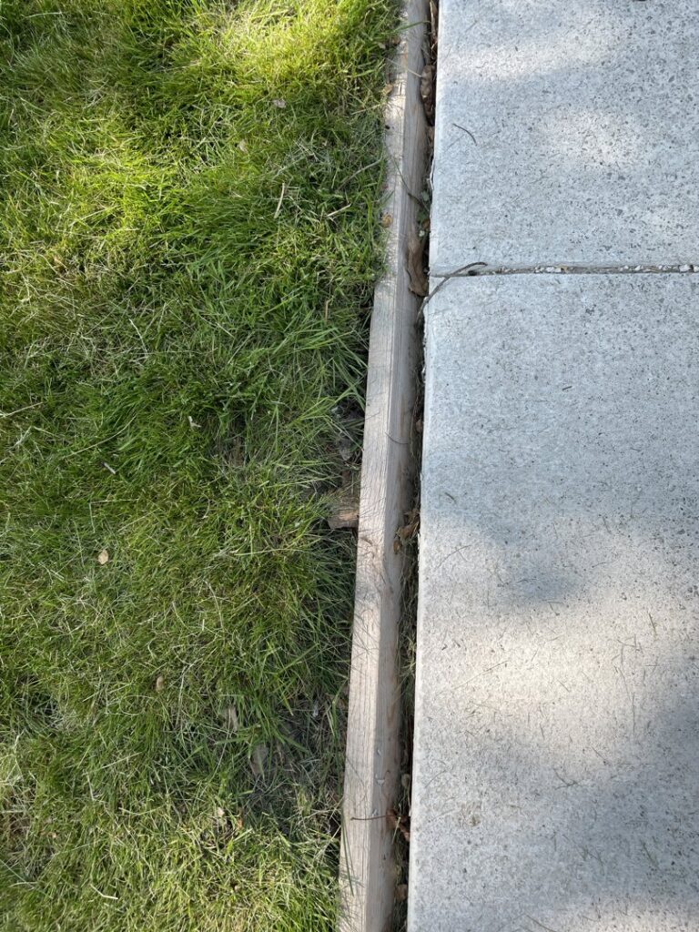A clean edge of a concrete slab with a wooden border, demonstrating quality work by concrete poured & installed - cp&i in Buffalo, NY.