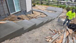 A worker smoothing newly poured concrete steps and a pathway by Blue Collar Service Pros in Aurora, CO.