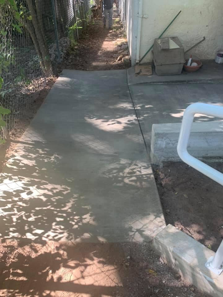 New concrete walkway and white handrail installed along a fence by Valdez Remodeling & Weatherization Inc. in Austin, TX