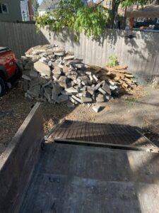 A large pile of broken concrete and wood debris next to a junk removal trailer from Mr. Groundhog Disposal and Services in Bloomington, MN.