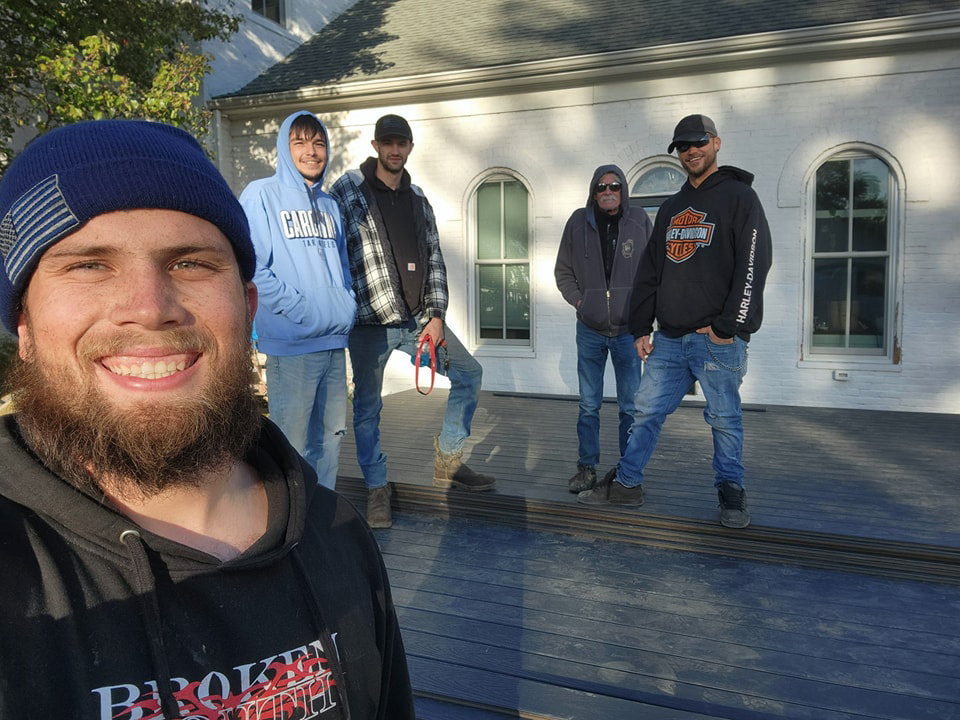 A construction crew posing on a newly built deck at a job site, representing Drew's Handy Construction team in Charleston, IL.