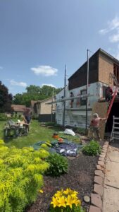 A construction crew working on house siding with scaffolding and ladders by Cedar Siding Repair in Centerville, OH.