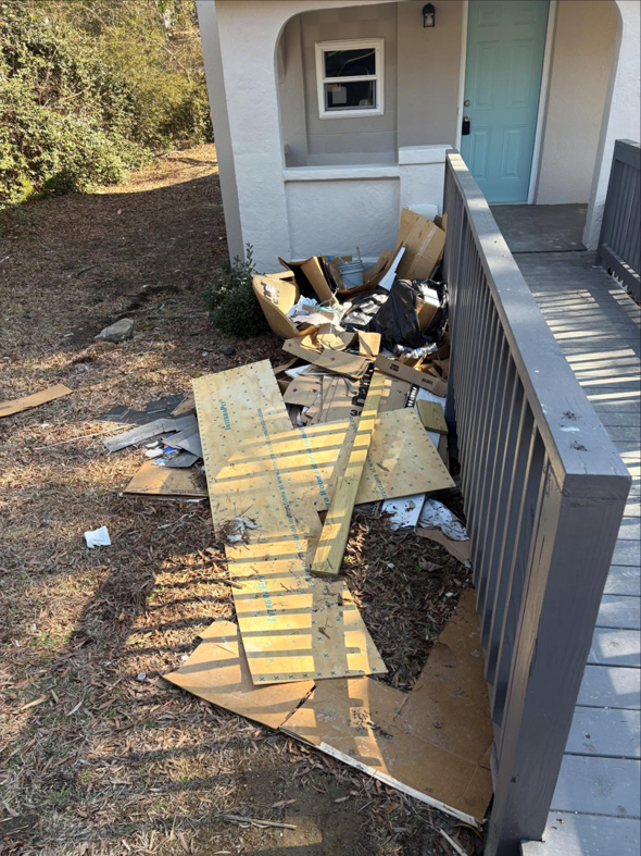 A pile of construction debris, wood, and cardboard boxes next to a house, ready for removal by JD Junk Removal in Raleigh, NC.