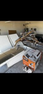 Construction debris, old bathroom fixtures, and boxes piled in a garage for removal by The Junkporter Junk Removal in Las Vegas, NV.
