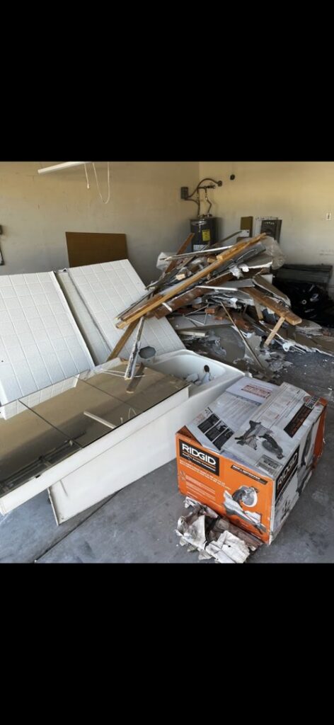 Construction debris, old bathroom fixtures, and boxes piled in a garage for removal by The Junkporter Junk Removal in Las Vegas, NV.