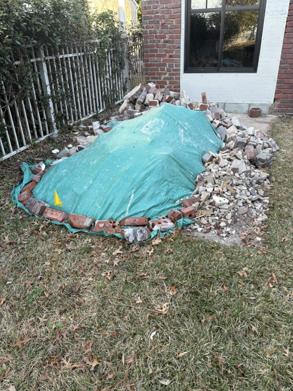A pile of broken bricks and construction debris covered by a tarp, ready for removal by EcoClear Junk Removal in Baltic, CT.