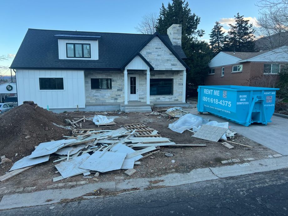 A blue dumpster from Blue Bin Dumpster Rentals collecting construction debris at a job site in Millcreek, UT.