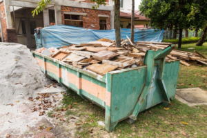 A green and orange dumpster filled with construction debris for Kwick Dumpster in Atlanta, GA