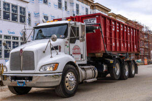 A Geppert Recycling truck with a large red dumpster at a construction site for debris removal in Philadelphia, PA.