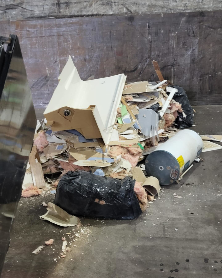 Construction debris like drywall, insulation, and a water heater inside a dumpster from Patriot Dumpster Rental in Chattanooga, TN.