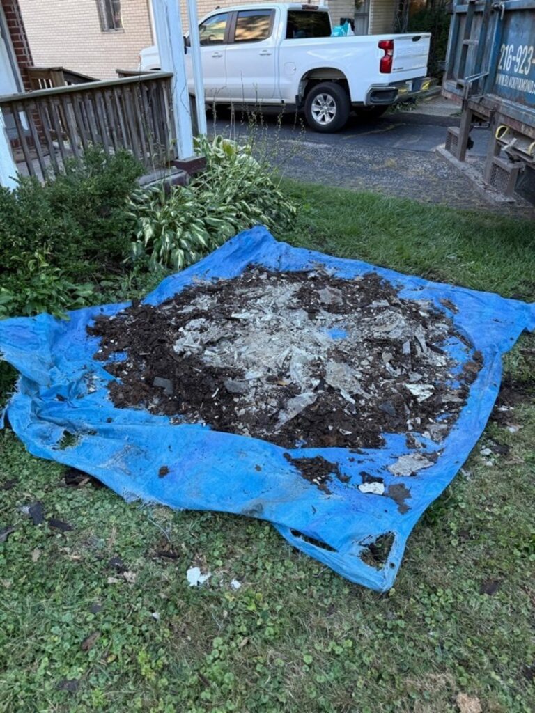 A pile of construction debris and dirt on a blue tarp for removal by Black Diamond Junk Removal in Bedford Heights, OH.