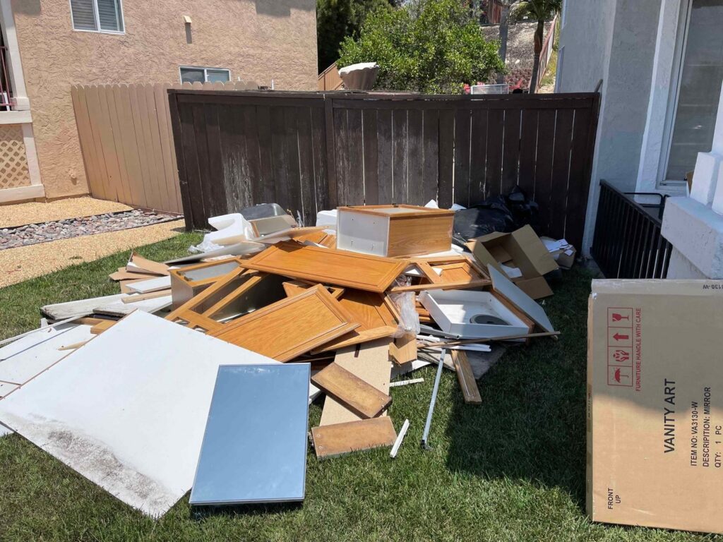 A pile of construction debris, including cabinet parts and wood, on a lawn for removal by Eastlake Hauling and Junk Removal, LLC in Chula Vista, CA.