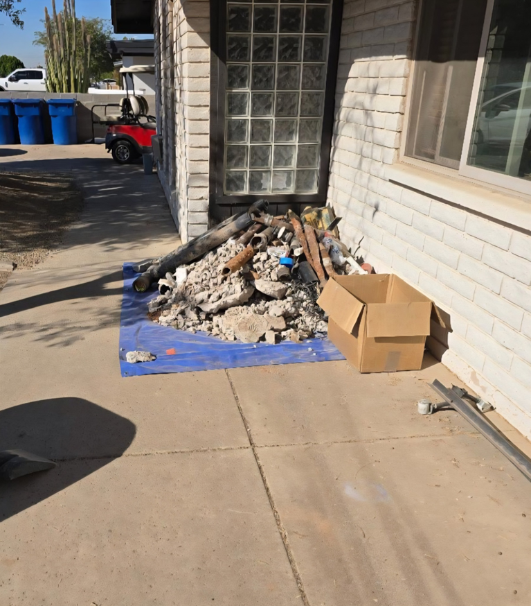 A pile of construction debris and pipes on a blue tarp, ready for removal by ALL around junk, LCC in Mesa, AZ.