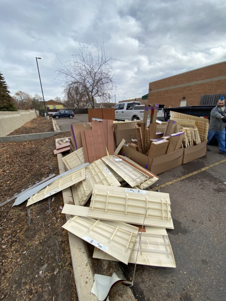 A large pile of construction debris, including wood and siding, in a parking lot, ready for removal by Hudson's Trash Removal, LLC in Great Falls, MT.
