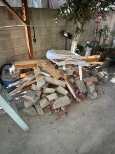 A pile of construction debris including bricks, wood, and concrete, ready for removal by L.A. Junk Squad in Bell Gardens, CA.