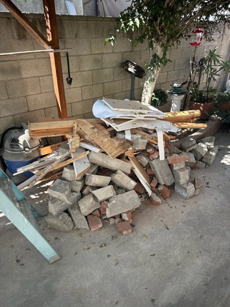 A pile of construction debris including bricks, wood, and concrete, ready for removal by L.A. Junk Squad in Bell Gardens, CA.