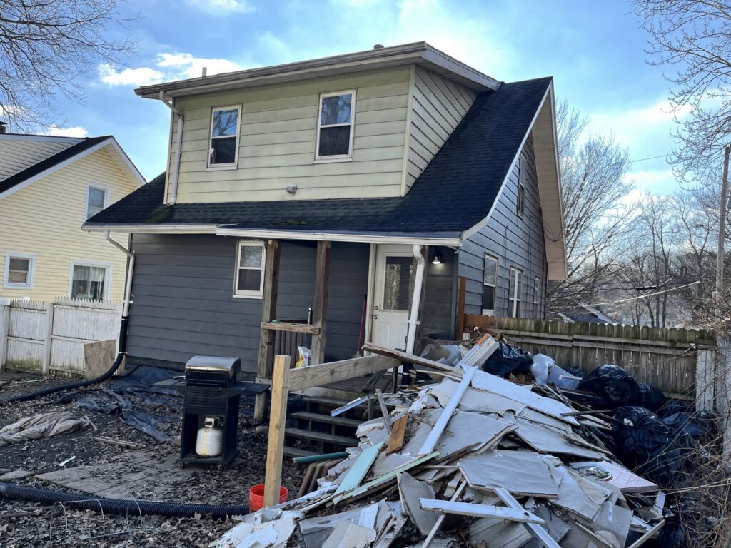 A large pile of construction debris, including drywall and wood, in the backyard of a house, ready for Sos Junk Removal in Akron, OH.