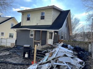 A large pile of construction debris, including drywall and wood, in the backyard of a house, ready for Sos Junk Removal in Akron, OH.