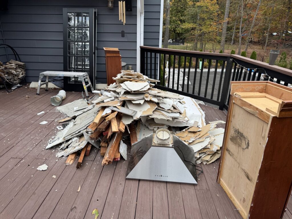 A large pile of construction debris, including drywall and wood, on a residential deck, ready for removal by Junkin Irishman in Wayne, NJ.