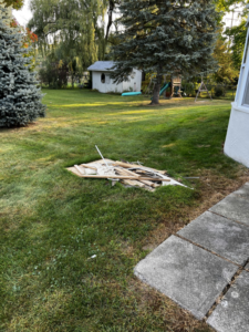 A small pile of construction debris and wood scraps on a green lawn, ready for removal by Junk Run 810 in Flint, MI.