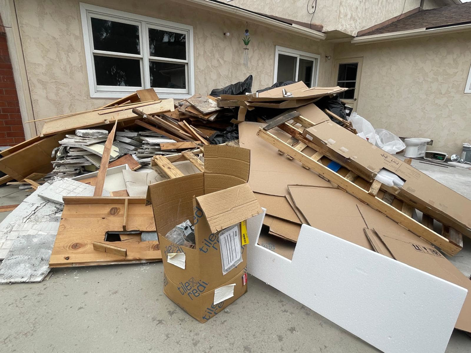A large pile of construction debris, including wood and cardboard, outside a home for NICOS Hauling in San Diego, CA.