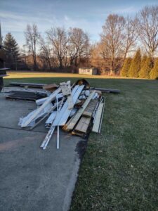 A large pile of construction debris, including wood and plastic, on a concrete driveway for removal by 1-800-Declutter in Cincinnati, OH.