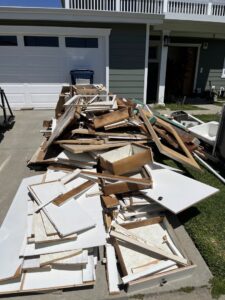 A large pile of construction and renovation debris on a driveway for removal by The Junk Gentlemen in Anaheim, CA.