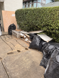 Piles of construction debris, black trash bags, and plywood awaiting removal by HB Junk Hauling LLC in Springfield, OR.