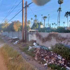 A large pile of construction debris and trash along an alley wall, ready for removal by All-Pro HAUL Property Services in Phoenix, AZ.