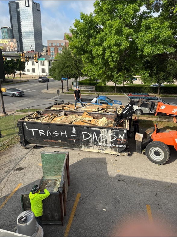 Workers loading construction debris into a large dumpster for removal by Trash Daddy in Fort Worth, TX