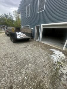 A dump trailer filled with construction debris next to a new house by CleanSite Solutions in Windham, ME.