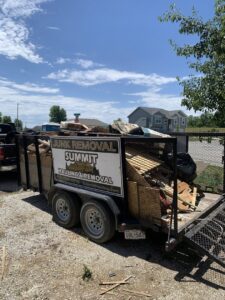 A Summit Hauling & Removal truck and trailer loaded with wooden pallets and construction debris in Lee's Summit, MO.