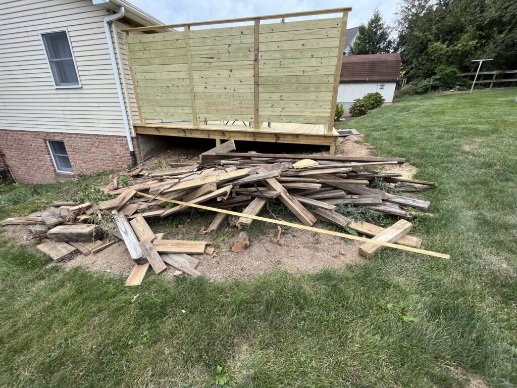 A pile of construction debris and wood scraps next to a deck, ready for removal by Junk Lockdown LLC in Lancaster, PA.