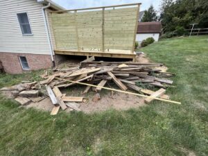 A pile of construction debris and wood scraps next to a deck, ready for removal by Junk Lockdown LLC in Lancaster, PA.